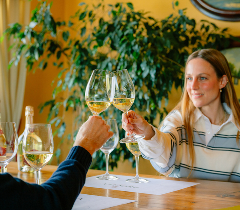 Albergo Diffuso Vinova - Degustazione di vino nel Gavi: due ospiti brindano in un'atmosfera calda e autentica. Esperienze offerte durante il soggiorno nelle Wine Suites Vinova.